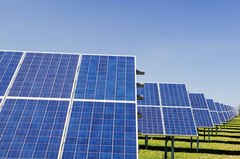 Painéis solares azuis alinhados sob céu limpo
